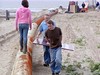 SundownIsland > Rebekah Olson walks along the dredge pipe, while Andrew and his Dad, Ed Olson carry the "posted sign" to be mounted.