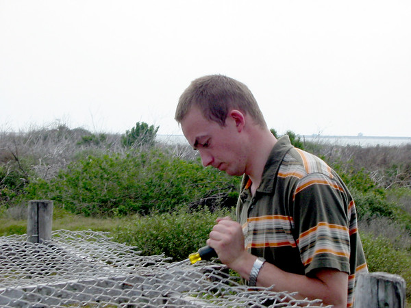 SundownIsland > Isaac Olson, who most likely helped build this nesting stand with his Dad, Ed Olson, tugs off the attached fencing. Isaac has been gone for two years on a church mission, but returned just in time to help with workday. When he was in high school, he did his Eagle Scout project on the island, planting trees for habitat. (Photo credit: Hannah Olson)