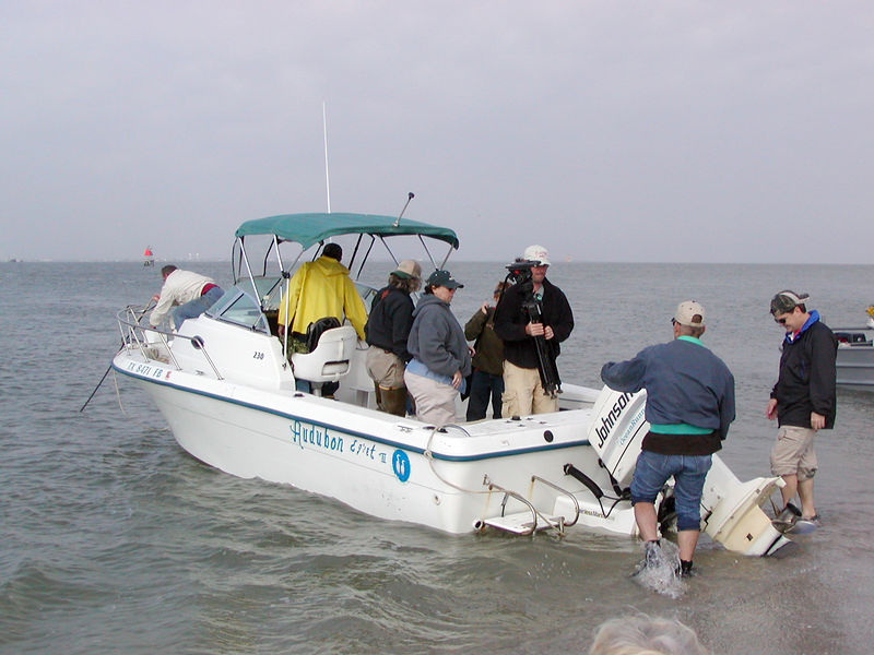 SundownIsland > The first crew arrives.  It was a windy choppy trip, typical for a March workday. Tim Wilkinson and his brother, Doug, help unload the boat while Diane Nunley, Marcy Spearsl, Ethan Vuichard and Abe Moore passed over supplies and equipment. Richard Prater (on bow) and Ed Taylor (yellow slicker) secure the Egret II. (Photo credit: Rebeka Olson)