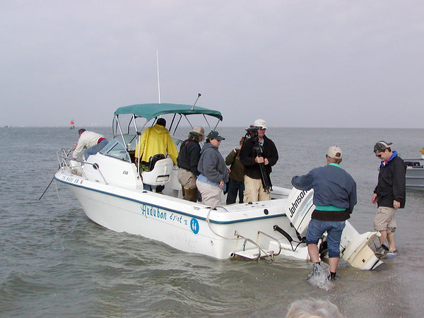 SundownIsland > The first crew arrives.  It was a windy choppy trip, typical for a March workday. Tim Wilkinson and his brother, Doug, help unload the boat while Diane Nunley, Marcy Spearsl, Ethan Vuichard and Abe Moore passed over supplies and equipment. Richard Prater (on bow) and Ed Taylor (yellow slicker) secure the Egret II. (Photo credit: Rebeka Olson)