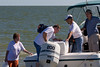 SundownIsland > Finally, the second crew arrives.  Devon Energy volunteers, Barbara Van Horn (left) prepares to carry items to shore while Dale Blakeman disembarks as Richard Brietzke prepares to hand him the cooler. Tim Wilkinson (far right) (son-in-law of Chester Smith) was our boat operator for the Fall Workday.   Photo credit: Marcy Crowe Spears