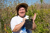 SundownIsland > Lynn Travis shows a small Ebony tree that is not much bigger than her hand.  Many of these have been planted on the island and have done well. The Ebony tree provides great habitat for the medium size birds. When full with occupants it looks like a condo.   Photo credit: Marcy Crowe Spears